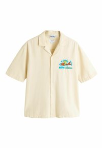 Kermanvärinen, lyhythihainen napillinen paita, jossa värikäs Keith Haringin grafiikka vasemmalla rinnalla: hahmo ratsastamassa punaisella koiralla.