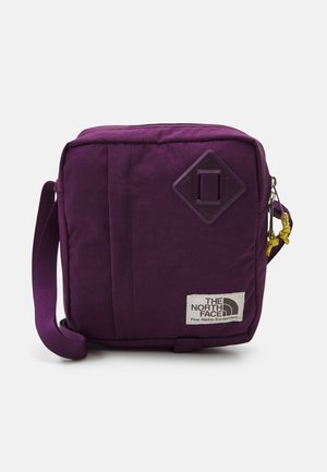 Fioletowa, kwadratowa torebka na ramię z regulowanym paskiem, zamkiem błyskawicznym z przodu, naszywką z logo "The North Face Fine Alpine Equipment" i detalem w kształcie diamentu.