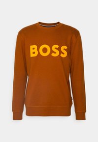 Sudadera marrón con cuello redondo, puños acanalados y un gran logotipo amarillo "BOSS" en el pecho. Material suave y liso.