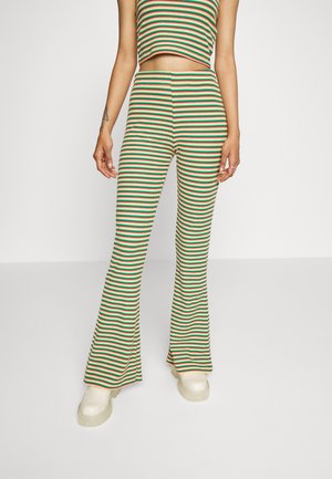 Top cropped riscado e calças largas em malha canelada nas cores verde, vermelho e bege. Apresenta uma cintura ajustada e aberturas largas nas pernas. Sapatos de plataforma em cor creme.