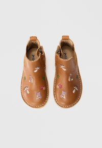 Barna bőrcipők, amelyek gombamintákkal, levelekkel és egy nyúllal hímezett motívumokkal díszítettek. Slip-on stílus, oldalhúzóval az egyszerű felvétel érdekében.