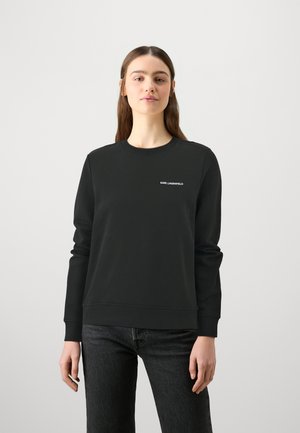 Felpa nera con collo tondo e maniche lunghe. Presenta un discreto logo bianco "KARL LAGERFELD" sul petto sinistro. Tessuto morbido.