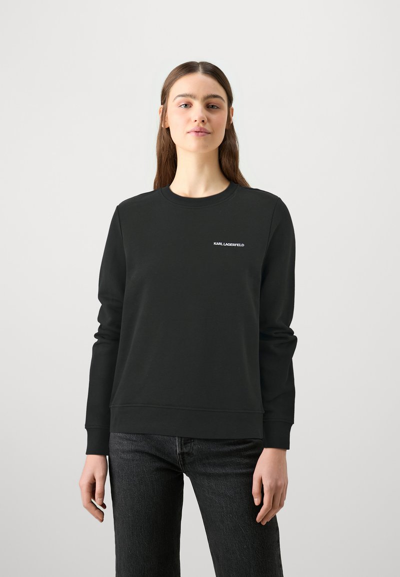 Felpa nera con collo tondo e maniche lunghe. Presenta un discreto logo bianco "KARL LAGERFELD" sul petto sinistro. Tessuto morbido.