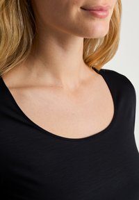 Zwarte, kortärmelige top met een brede ronde hals. Glad, lichtgewicht materiaal met een subtiele textuur en een aansluitend ontwerp.