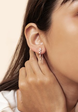 Silver chain earrings with clustered sparkling gemstones. The design features a cascading style, accentuating a modern, delicate look.