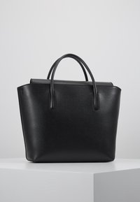 Svart läderhandväska med strukturerad form, slät yta, två handtag och en vikflik upptill.