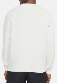 Witte sweatshirt van zachte stof, met een ronde halslijn en ribgebreide boorden. De achterkant is eenvoudig zonder extra patroontjes of details.