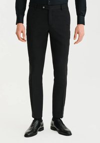 Czarne dopasowane spodnie o prostym kroju, wykonane z gładkiego materiału, z zapięciem na guzik i subtelnymi fałdami z przodu. W połączeniu z czarnymi eleganckimi butami.