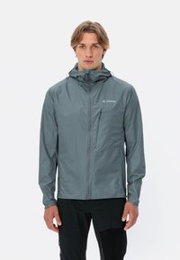Giacca leggera grigia con cappuccio, chiusura a zip sul davanti e piccola tasca sul petto. Realizzata in materiale resistente all'acqua; texture liscia e design aderente.