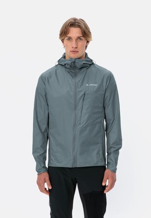 Giacca leggera grigia con cappuccio, chiusura a zip sul davanti e piccola tasca sul petto. Realizzata in materiale resistente all'acqua; texture liscia e design aderente.