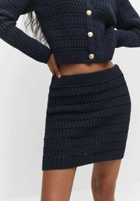 Set due maglia blu navy composto da un cardigan corto con bottoni dorati tondi e una gonna aderente con motivi testurizzati orizzontali.