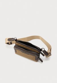 Καφέ τσάντα χιαστί με μοτίβο, δύο διαμερίσματα με φερμουάρ, δερμάτινες λεπτομέρειες και ρυθμιζόμενο μπεζ λουρί. Διαθέτει λογότυπο στο μπροστινό μέρος.