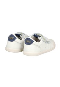 Zapatillas blancas para niños pequeños con parches en el talón de color azul marino que muestran "igor" y "1974", con tiras de Velcro y suelas de goma.