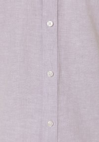 Light purple linen shirt featuring a button-up design with white buttons and a textured fabric. Close-up view focuses on the button area.
