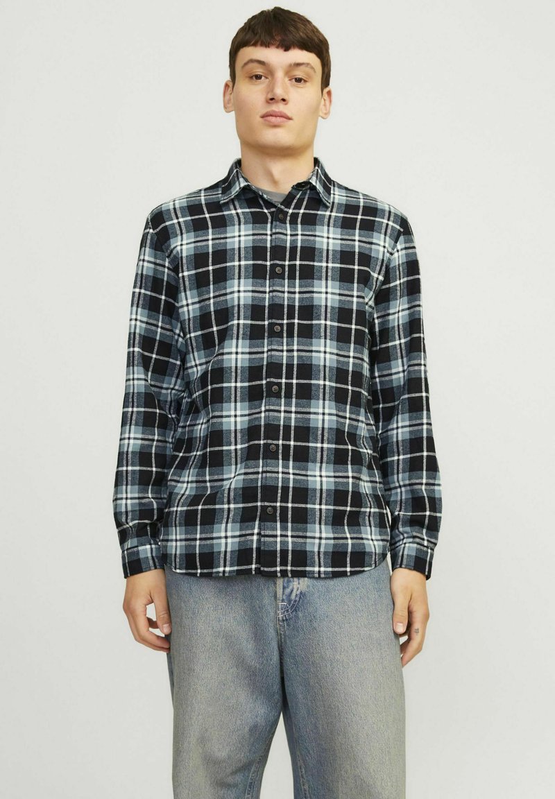 Camisa de franela a cuadros en negro y azul con diseño de botón, mangas largas y cuello. La tela parece suave y tiene un patrón a cuadros.