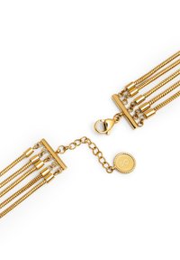 Bracciale multi-strato dorato con catene metalliche testurizzate, chiusura a pulsante e un ciondolo circolare con logo in rilievo.