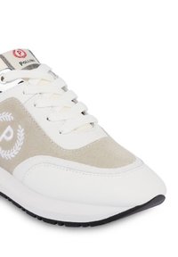 Sneaker bianco con sovrapposizione in suede beige, un logo e lacci testurizzati. La suola è nera con un intersuola bianca per contrasto.