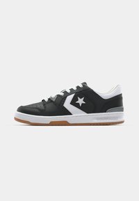 Black leather sneaker with white accents, featuring a star logo, white laces, and a gum sole. Classic low-top design with perforated details.