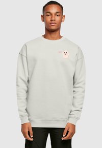 Light gray sweatshirt made of soft fabric, featuring a pink ghost graphic and the text "Boo!" on the left chest. Ribbed cuffs and hem.