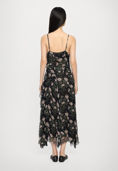 Robe maxi noire à fleurs avec des bretelles spaghetti, ornée de fleurs rose et blanche et de vignes vertes. Tissu transparent avec une silhouette fluide.