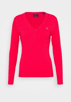Pull V à col en V rose vif avec un motif en tricot torsadé, manches longues et un ourlet côtelé ajusté. Logo GANT sur la poitrine gauche. Matériau en coton.