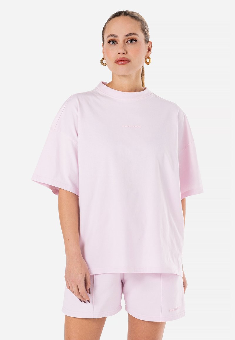 T-shirt en coton rose avec des manches courtes, un col montant et un logo brodé sur la poitrine, associé à un short assorti. Texture douce.