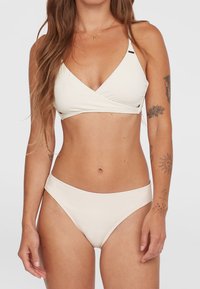 Bielo-čierny bikiny set s vrchným dielom v zaväzovacom štýle s tenkými ramienkami a zodpovedajúcimi stredne vysokými spodnými dielmi. Hladká textura s minimálnymi akcentmi.
