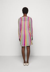 Abito a strisce multicolori con maniche lunghe, scollo rotondo e vestibilità ampia. I colori includono rosa, blu, giallo e oro.