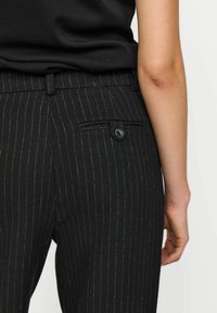 Zwarte broek met streepje in een gemêleerde stof, met een achterzak met knoopsluiting en een standaard tailleband.