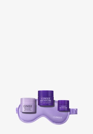 Tre Clinique hudplejebeholdere i lys og mørk lilla hviler på en matchende lilla sovemaske med Clinique-logoen.