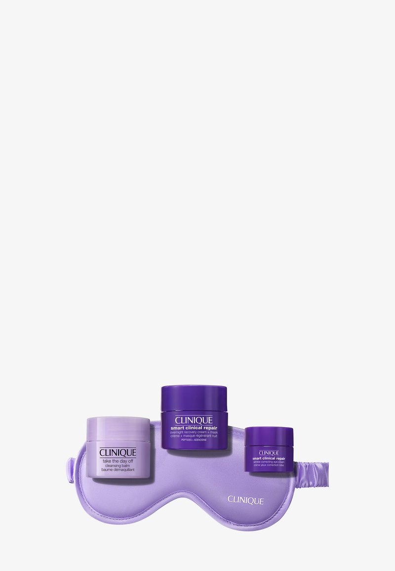 Drie Clinique huidverzorgingspotjes in licht- en donkerpaars liggen op een bijpassend paarse slaapmasker met het Clinique-logo.