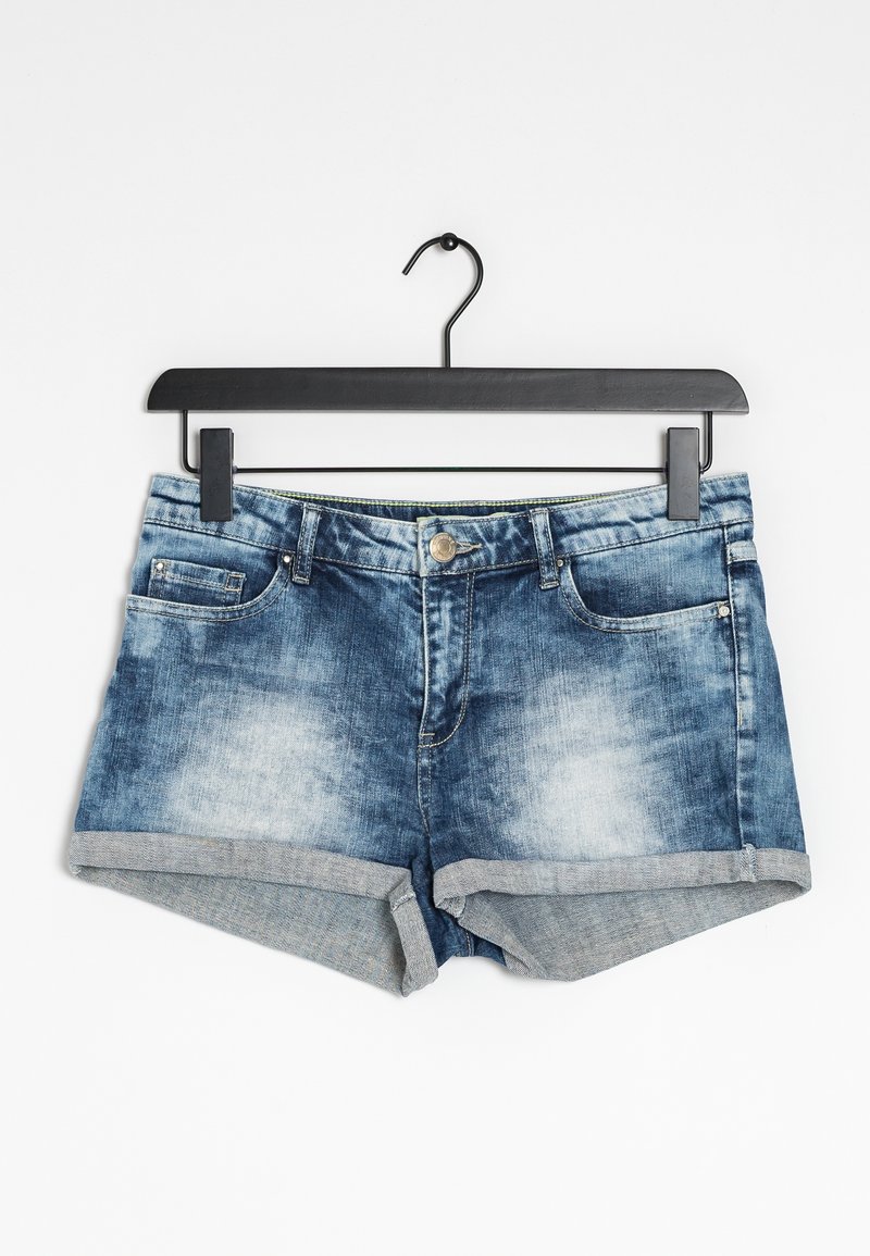 Blue denim shorts with rolled hems hanging on a black hanger against a white background.