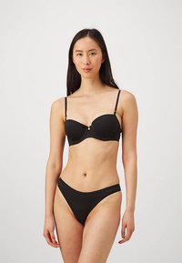 Ensemble de lingerie noire comprenant un soutien-gorge balconnet rembourré avec de fines bretelles réglables et un slip bikini taille basse assorti, tous deux en tissu lisse.