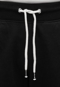 Μαύρο παντελόνι φόρμας με λευκό κορδόνι με μεταλλικές άκρες, ραβδωτή μέση και απαλό βαμβακερό υλικό.
