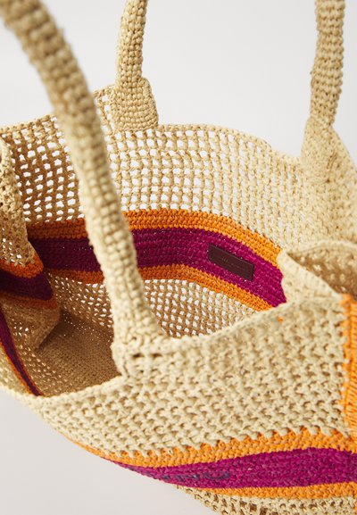 Geflochtene Tragetasche in natürlichem Beige mit lebhaften, orangefarbenen, pinkfarbenen und lila gestreiften Akzenten. Verfügt über robuste Griffe und eine offene Oberseite.