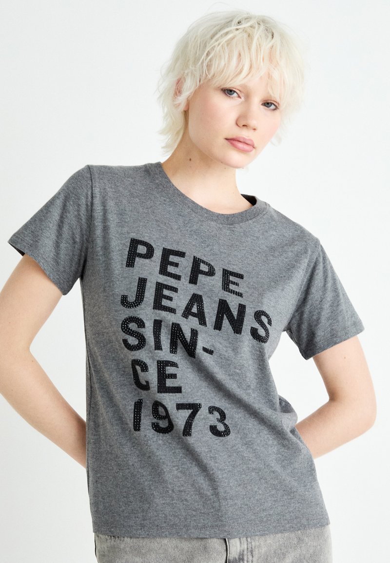 Camiseta de algodón gris con texto negro en negrita "PEPE JEANS SINCE 1973", mangas cortas y un cuello redondeado clásico.