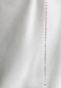 Silver chain necklace with a line of small, sparkling gemstones, featuring a larger gemstone pendant at the end, against a light background.