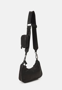 Sac à bandoulière en cuir noir avec une forme courbée. Comprend une pochette détachable, une sangle réglable et des accents en métal. Motif subtilement embossé.