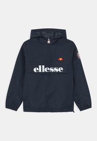 Granatowa kurtka przeciwdeszczowa z kapturem, pół-zamek z przodu, elastyczne mankiety, duża kieszeń z przodu oraz białe logo "ellesse" z czerwoną i pomarańczową emblematem.