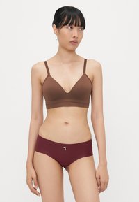 Bralette marrone con design a V e spalline sottili, abbinato a slip hipster marsala con logo bianco. Tessuto liscio con cuciture minime.