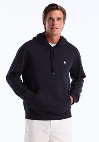 Hoodie bleu marine en tissu doux, doté d'une poche kangourou et d'un petit logo sur la poitrine. Il est équipé d'une capuche avec cordon de serrage pour un ajustement personnalisé.