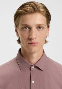 Rot-weiß gemustertes Hemd mit einem strukturierten Kragen, das an der Vorderseite Knöpfe hat. Das Material erscheint glatt mit einer feinen Textur.