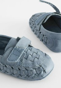 Chaussures en cuir bleu avec texture tissée, bout arrondi et bande Velcro. Elles disposent d'une semelle flexible et d'une doublure intérieure douce pour le confort.