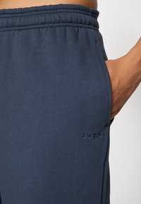 Navy zilas sporta šorti, kas izgatavoti no mīksta auduma, ar elastīgu jostu, sānu kabatu un diskrētu "BORG" logo izšuvumu.