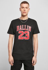 Juodas medvilnės marškinėliai su užrašu „BALLIN“ ir „23“, atspaustais ryškiai raudonomis raidėmis. Trumpomis rankovėmis, apvaliu kaklu, laisvo kirpimo. Nešiojama sidabrinė grandinėlė.