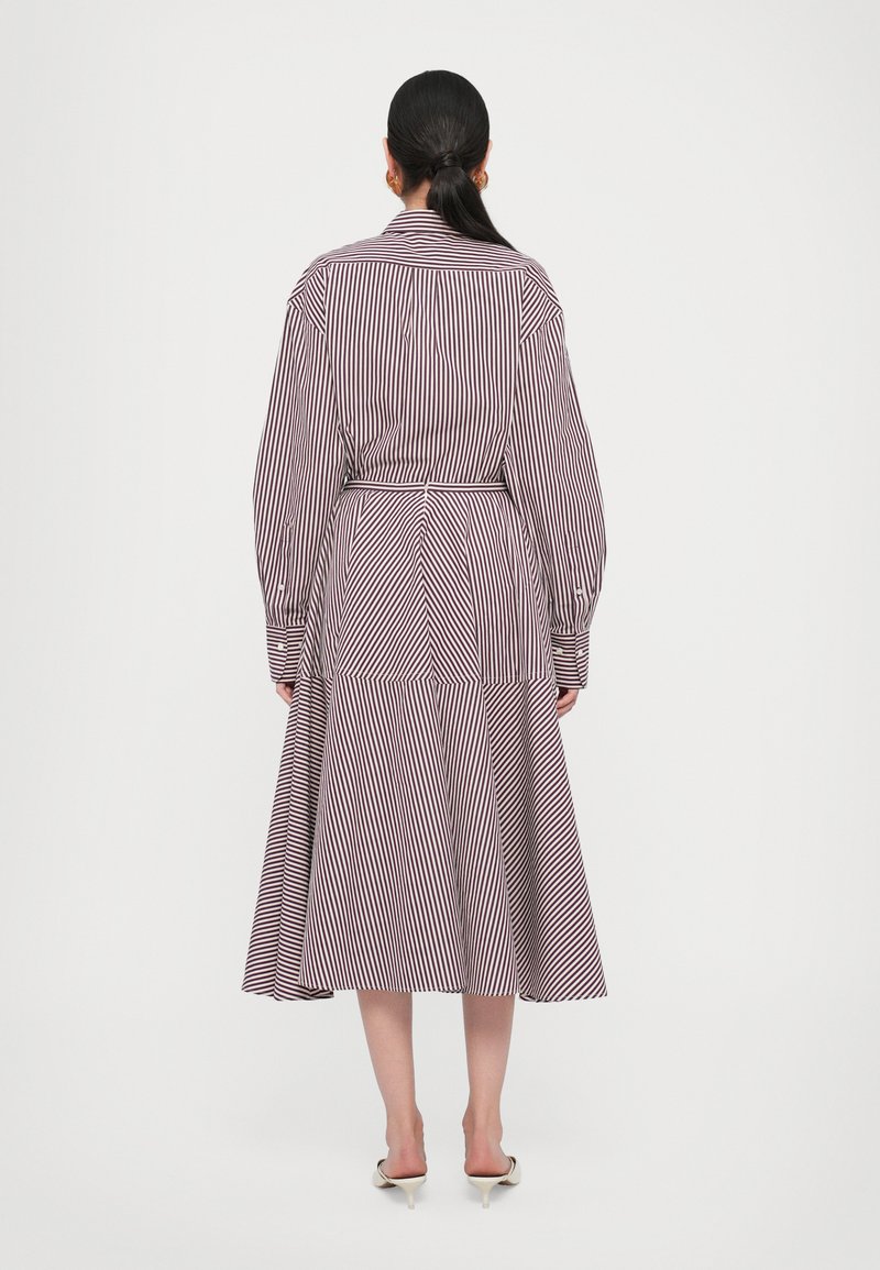 Randig klänning i mörkröd och vit, med knäppning bak, långa ärmar, insvängd midja och flödande kjol med plisserad design.