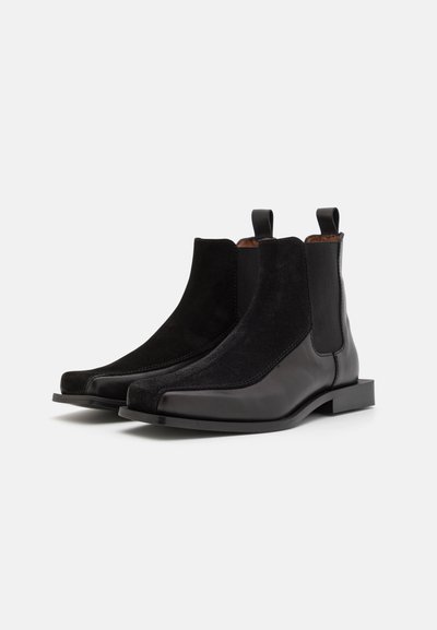 Bottines Chelsea en cuir noir et suède au design élégant, avec des panneaux latéraux élastiques et des languettes pour un enfilage facile. Forme de orteil carrée.