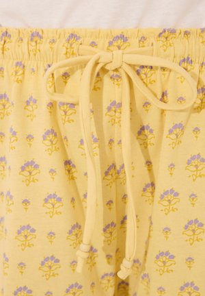 Gele katoenen broek met een elastische tailleband, voorzien van een bloemenpatroon in paars en geel. Zachte textuur, casual ontwerp dat geschikt is voor loungekleding.