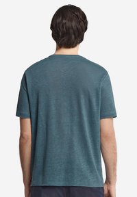 Kortärmad T-shirt i teal i mjukt, texturerat tyg, med rund halsringning och rak fåll utan synliga mönster eller detaljer.