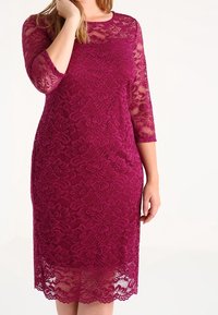 Burgundy spetsklänning med trekvartsärmar, blommönster och rundad halsringning. Har en knälång fåll med scallopade kanter.